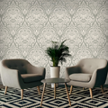 Two gray chairs with a small table and plant against a decorative wallpaper.