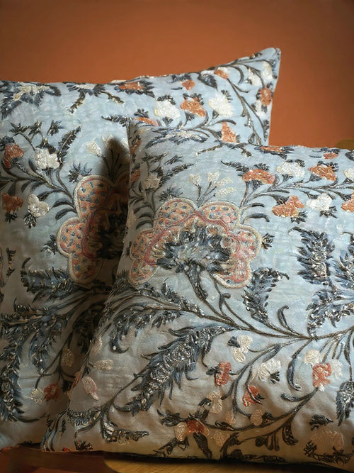 Decorative pillows with floral embroidery on a plain background