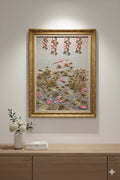 Decorative wall art with floral elements in a gold frame on a light gray wall.