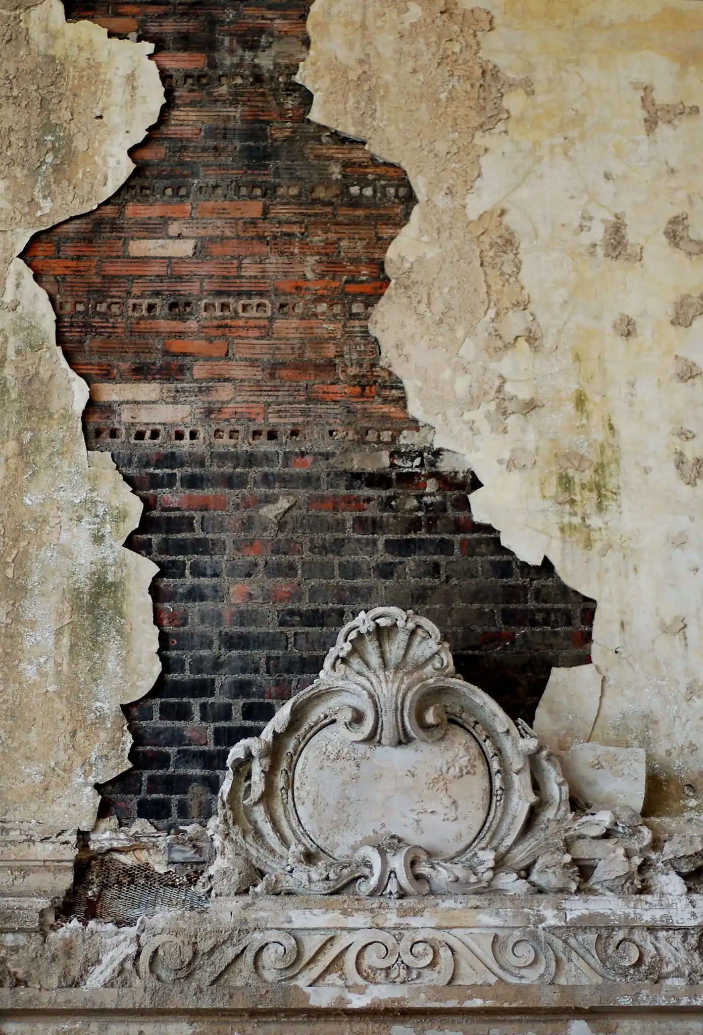 Decorative stone mantelpiece against a deteriorated brick wall
