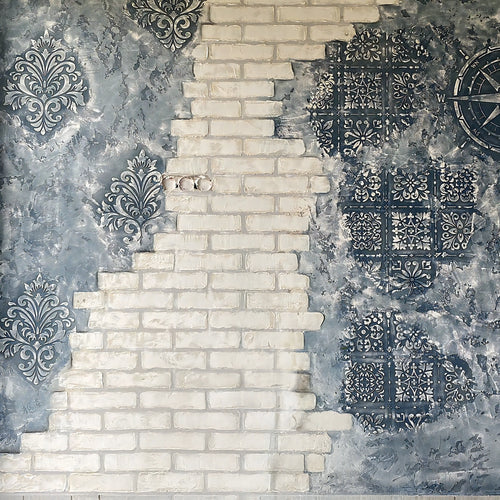 Decorative wall with a mix of brick pattern and ornate black designs on a gray background
