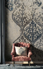 Pink armchair with a decorative pillow against a patterned wall.