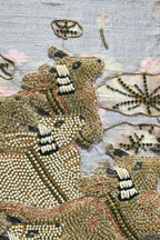 Close-up of a beaded animal figure with intricate patterns on a textured background