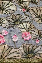 Close-up of embroidered fabric with floral patterns and pink flowers on a textured background.
