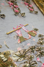 Close-up of decorative elements on a fabric background with gold and pink accents.