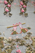 Close-up of intricate embroidery with floral and leaf patterns on a textured fabric background.