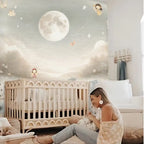 Woman sitting next to a crib in a nursery with a moon and star mural on the wall.