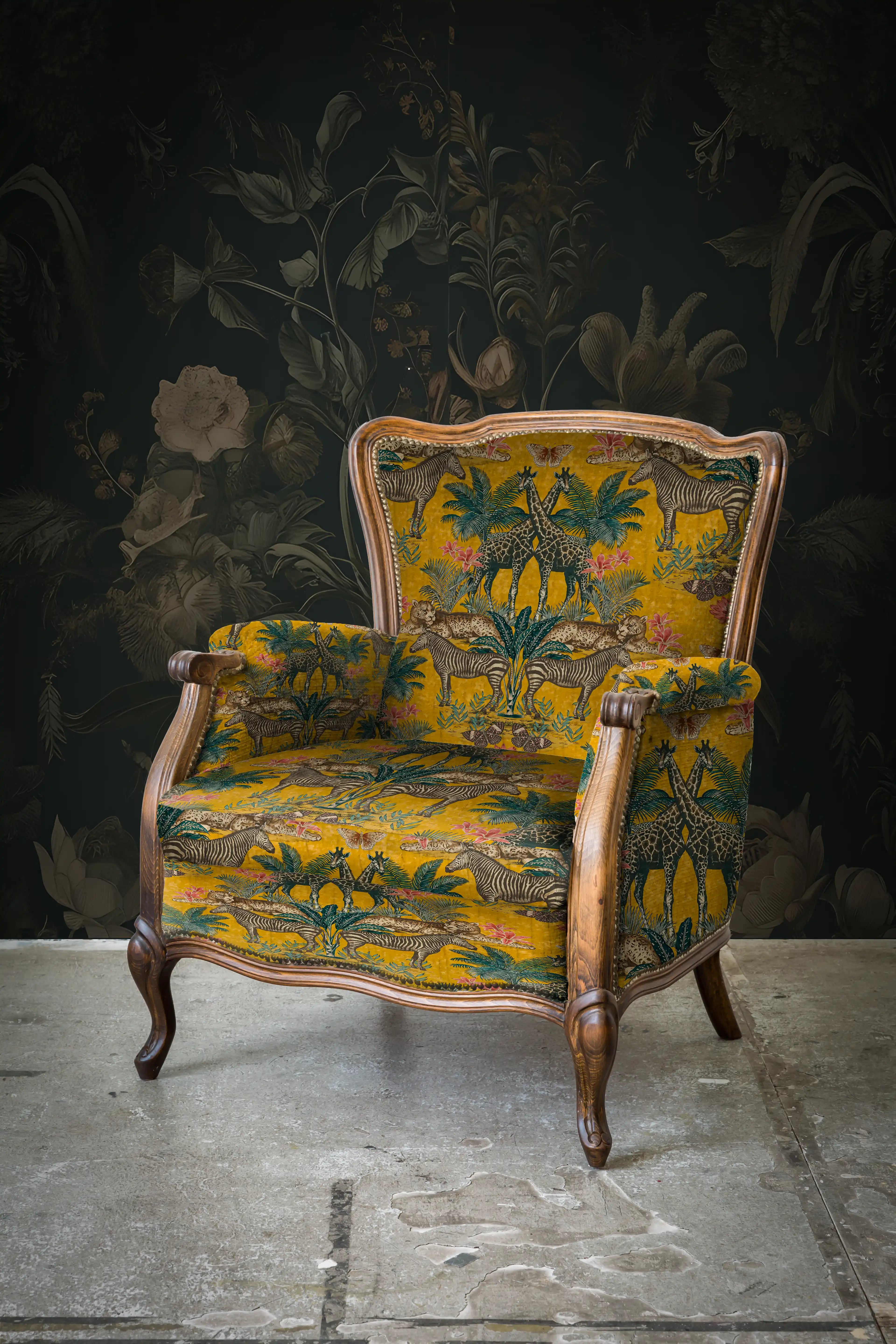 Decorative armchair with floral pattern against a dark floral wallpaper.