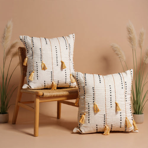 Decorative pillows with tassels on a wooden chair against a beige background